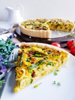 Asparagus, Leek and Tempeh Bacon Quiche in a tender Biscuit Crust sliced on white plate
