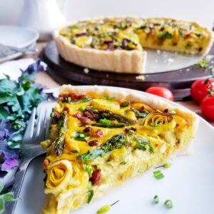 Asparagus, Leek and Tempeh Bacon Quiche in a tender Biscuit Crust sliced on white plate
