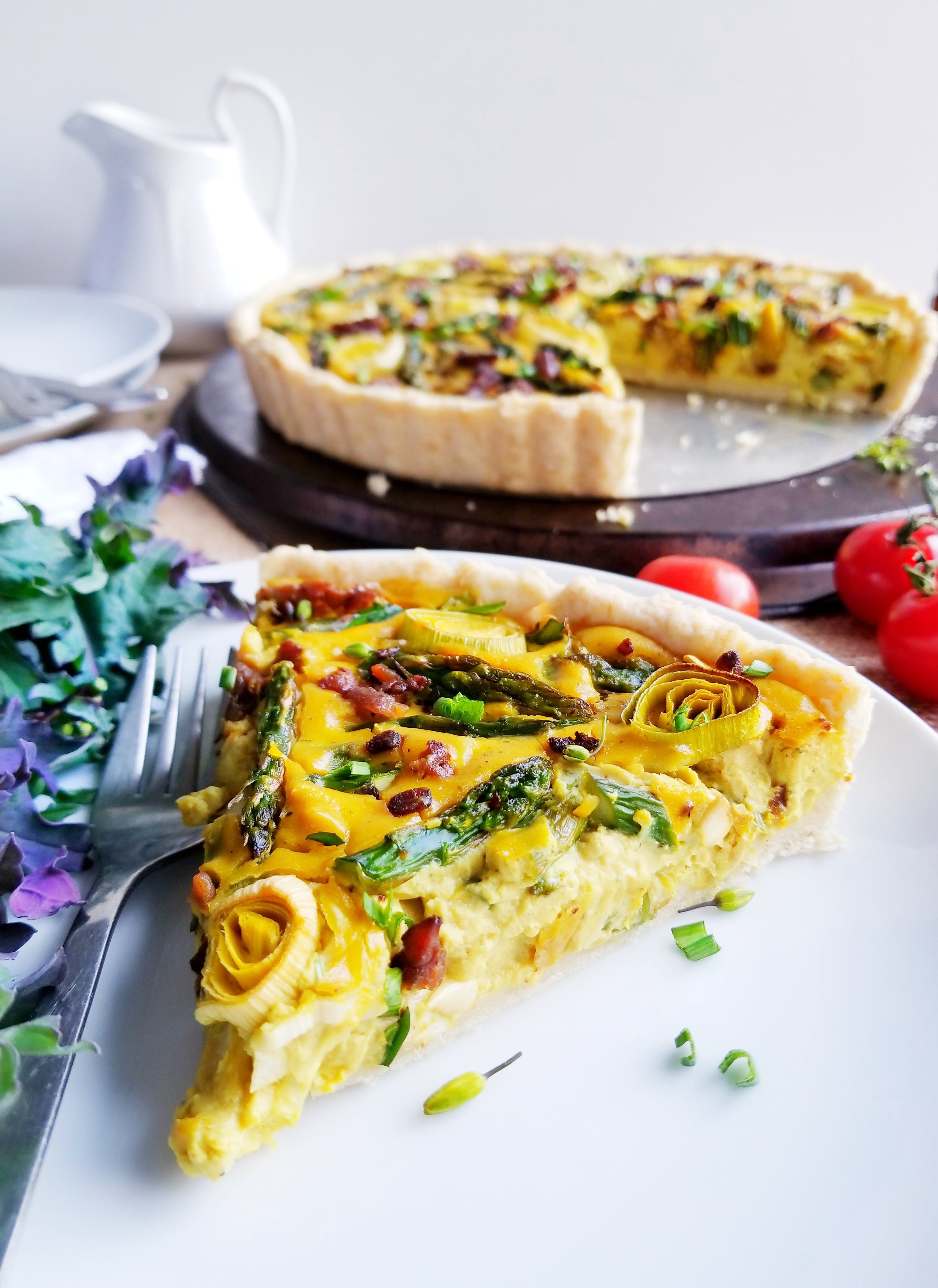 Asparagus, Leek and Tempeh Bacon Quiche in a tender Biscuit Crust sliced on white plate