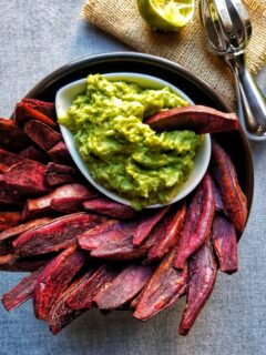 purple sweet potato wedges in a black bowl with guacamole