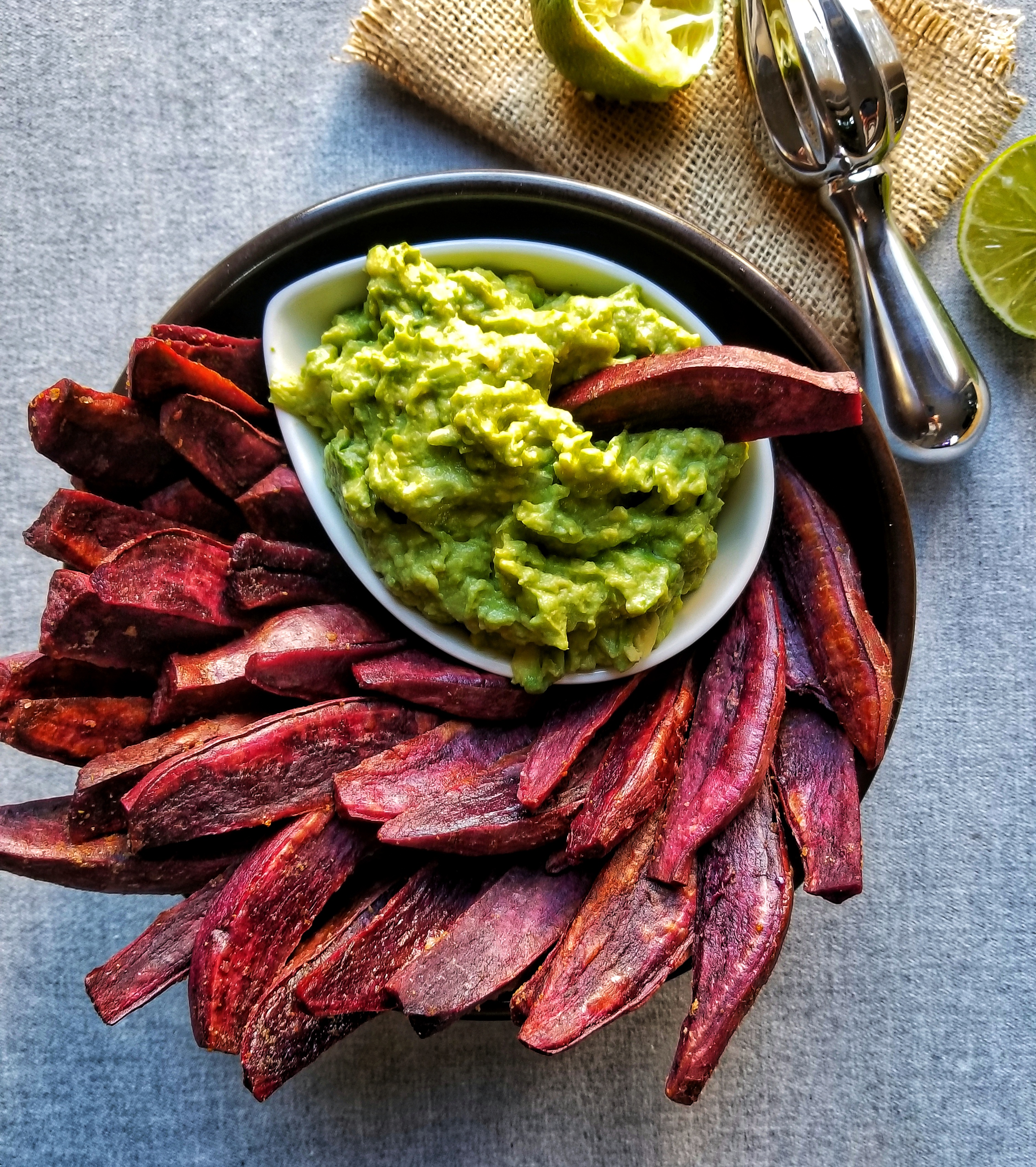 purple sweet potato wedges in a black bowl with guacamole