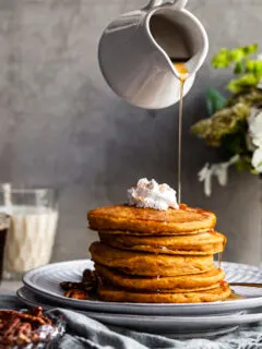 Stack of Pancakes on a plate being drizzled with maple syrup