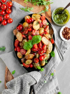 Roasted Baby Potatoes with Basil Pesto and Cherry Tomato Bruschetta being served with extra pesto and chilil flakes