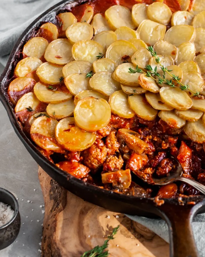 Vegan Savory Skillet Stew with Baby Potato Topping being served from skillet