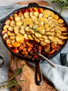Vegan Savory Skillet Stew with Baby Potato Topping with a serving scooped out of the skillet