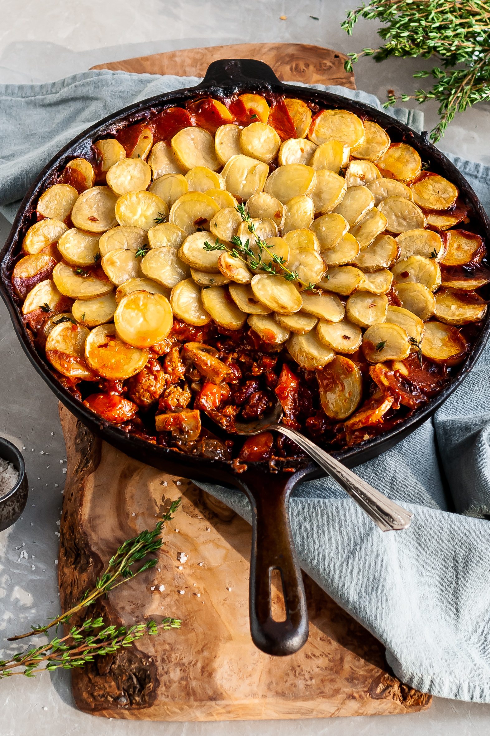 Vegan Savory Skillet Stew with Baby Potato Topping with a serving scooped out of the skillet