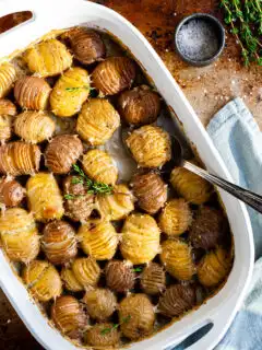 white casserole dish with baby hasselback potatoes in a creamy sauce