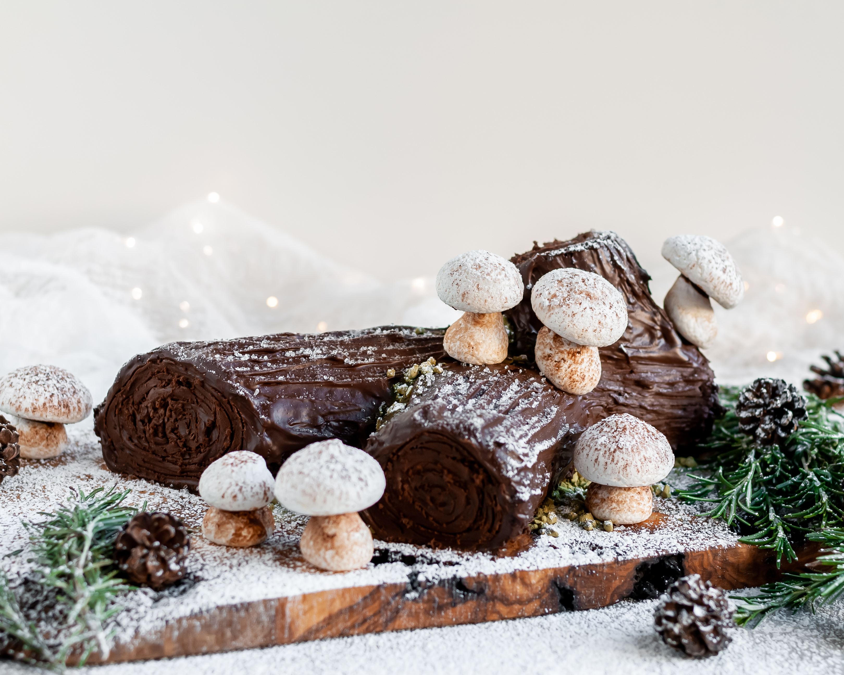 Vegan Chocolate Yule Log with Meringue Mushrooms served on a plank covered in icing sugar 