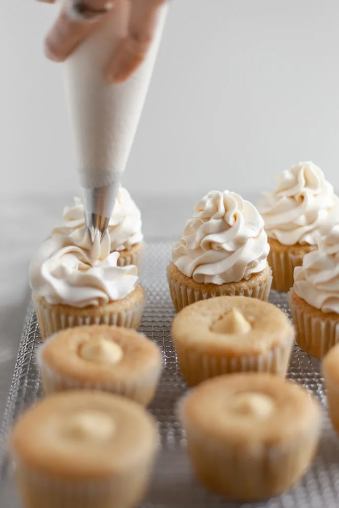 Vegan Coconut Cream Cupcakes being topped with coconut frosting