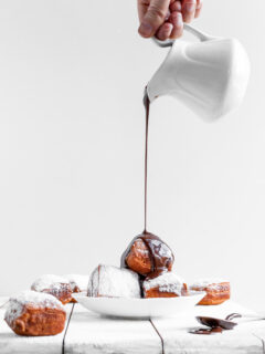 Vegan Beignets being covered in chocolate sauce