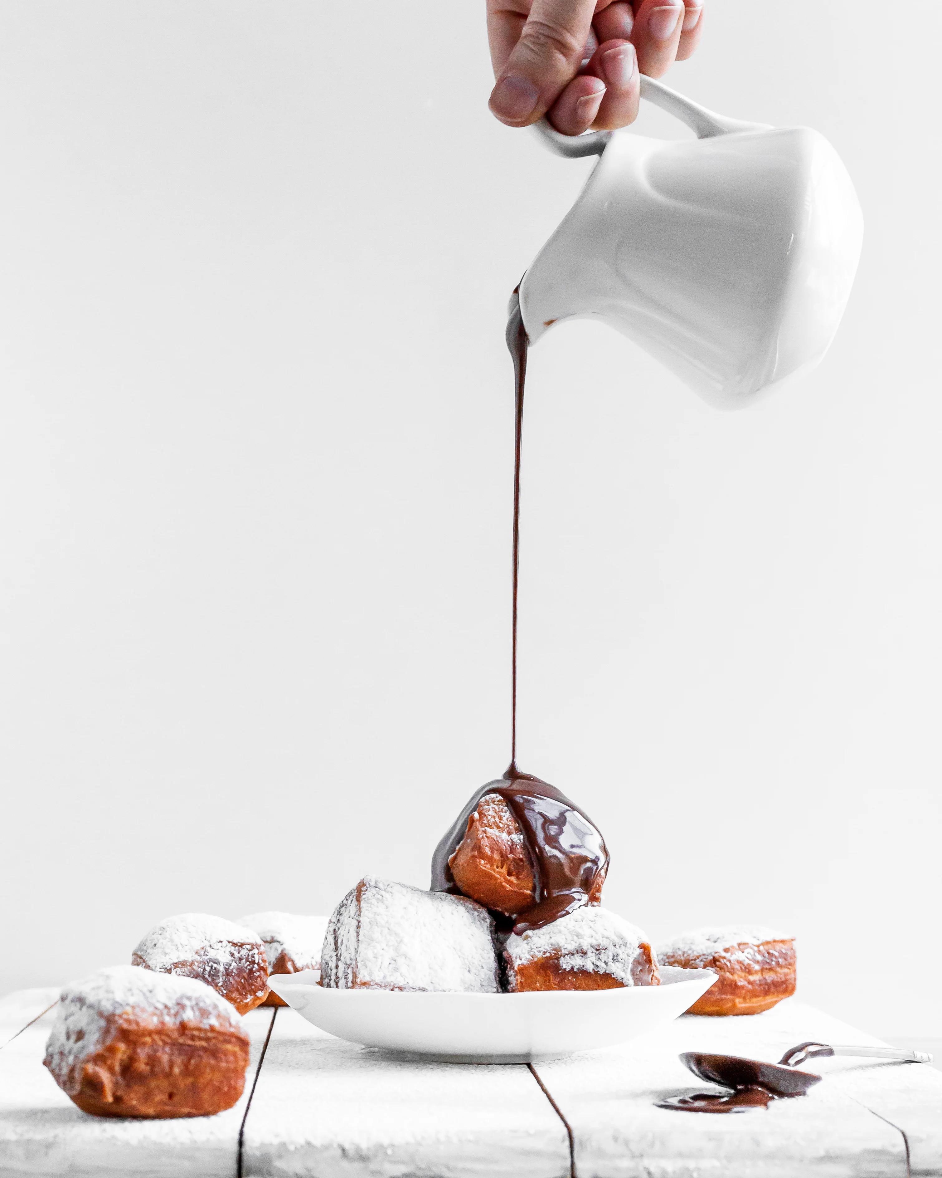 Vegan Beignets being covered in chocolate sauce