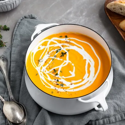 Creamy Curried Carrot, Ginger and Red Lentil Soup in pot with a swirl of coconut milk