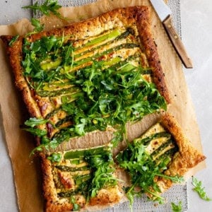 Vegan Asparagus and Pesto Cashew Cheese Tart with Lemon Arugula on colling rack and 2 pieces cut