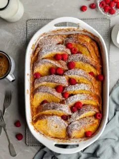 Vegan Lemon Raspberry French Toast Bake in white baking dish, garnished with fresh raspberries