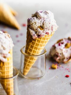 Vegan Strawberry Rhubarb Crumble Ice Cream in a waffle cone, set in a glass and other cones around it