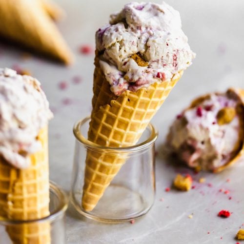 Vegan Strawberry Rhubarb Crumble Ice Cream in a waffle cone, set in a glass and other cones around it