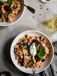 Mushroom Stroganoff served in white bowls, arnished with almond ricotta and parsley
