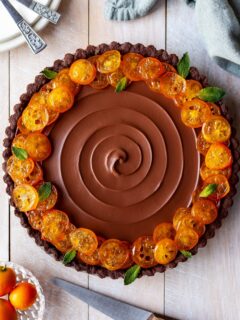Flatlay of Vegan Chocolate Orange Tart with Candied Kumquats, ready to be sliced and served