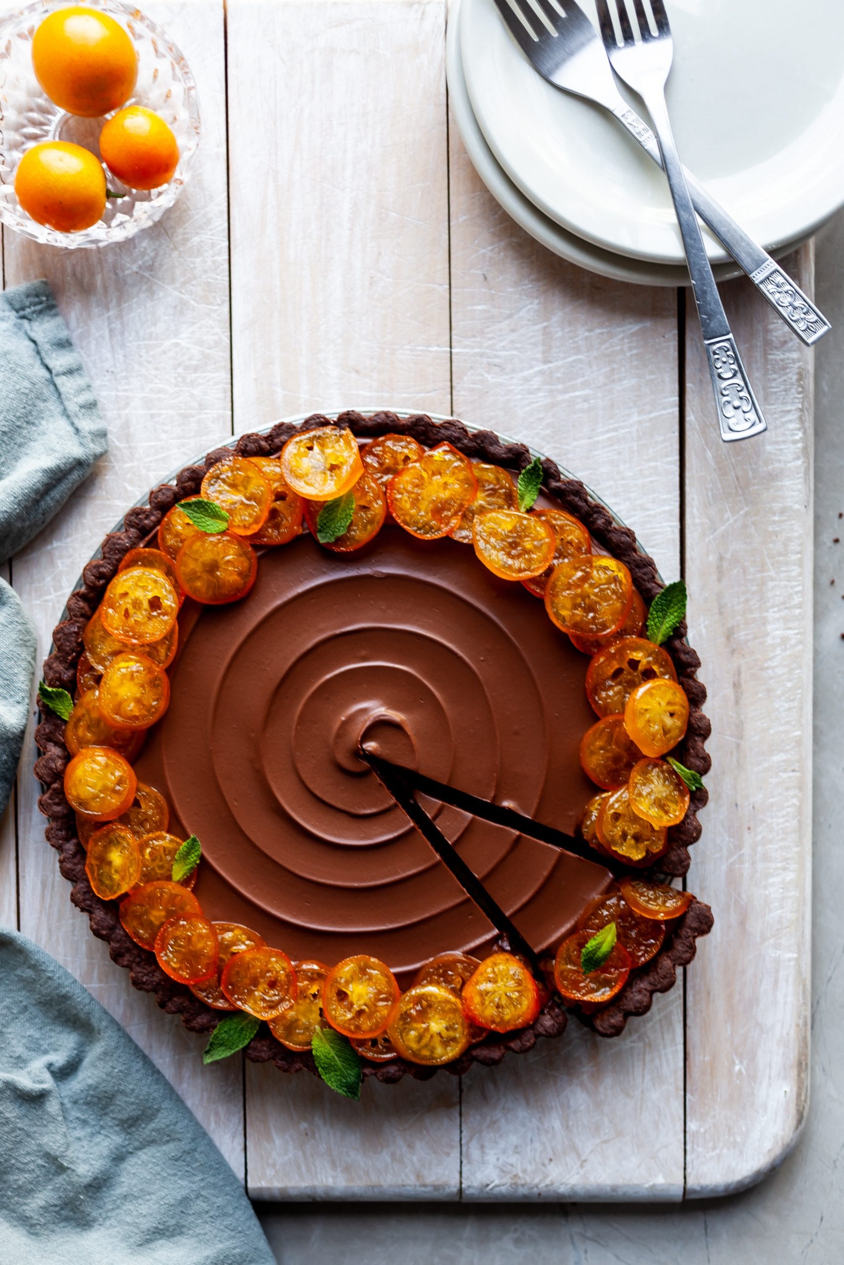 Vegan Chocolate Orange Tart with Candied Kumquats with one slice ready to be served on a white plate