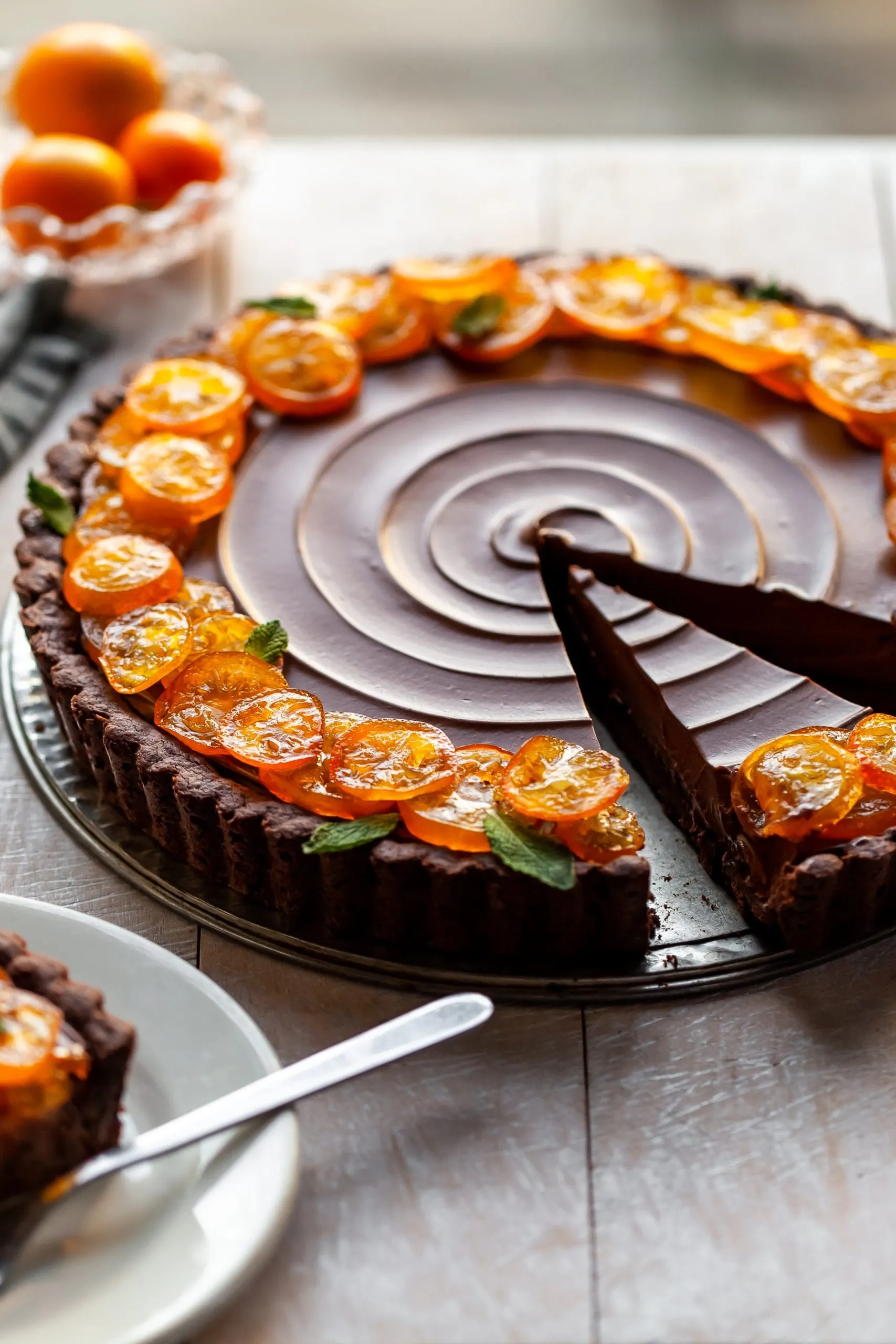 Vegan Chocolate Ornage Tart with Candied Kumquats with 2 slices cut, one is already served on a white plate