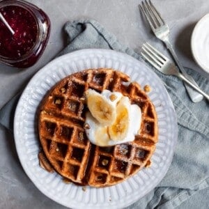 Vegan Banana Waffle on breakfast table served with fresh bananas and maple syrup