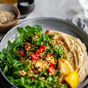 Herby Farro and Grilled Vegetables Salad served over Hummus with fresh lemon wedges and dukkah