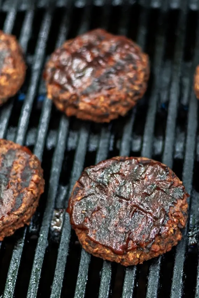 Veggie burgers on grills with grill marks and barbecue sauce