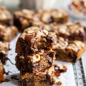 3 Vegan Chocolate Chunk Blondies stacked with a bite taken out of the top one