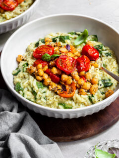 Bowl of risotto toppped with roasted cherry tomatoes and chickpeas which are covered in Everything Spice