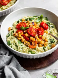 Bowl of risotto toppped with roasted cherry tomatoes and chickpeas which are covered in Everything Spice