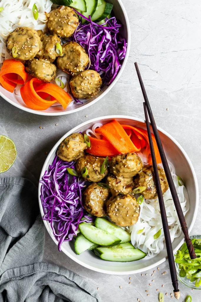 2 bowls of Asian-inspired chickpeas balls, rice noodles and fresh veggies with coconut curry sauce