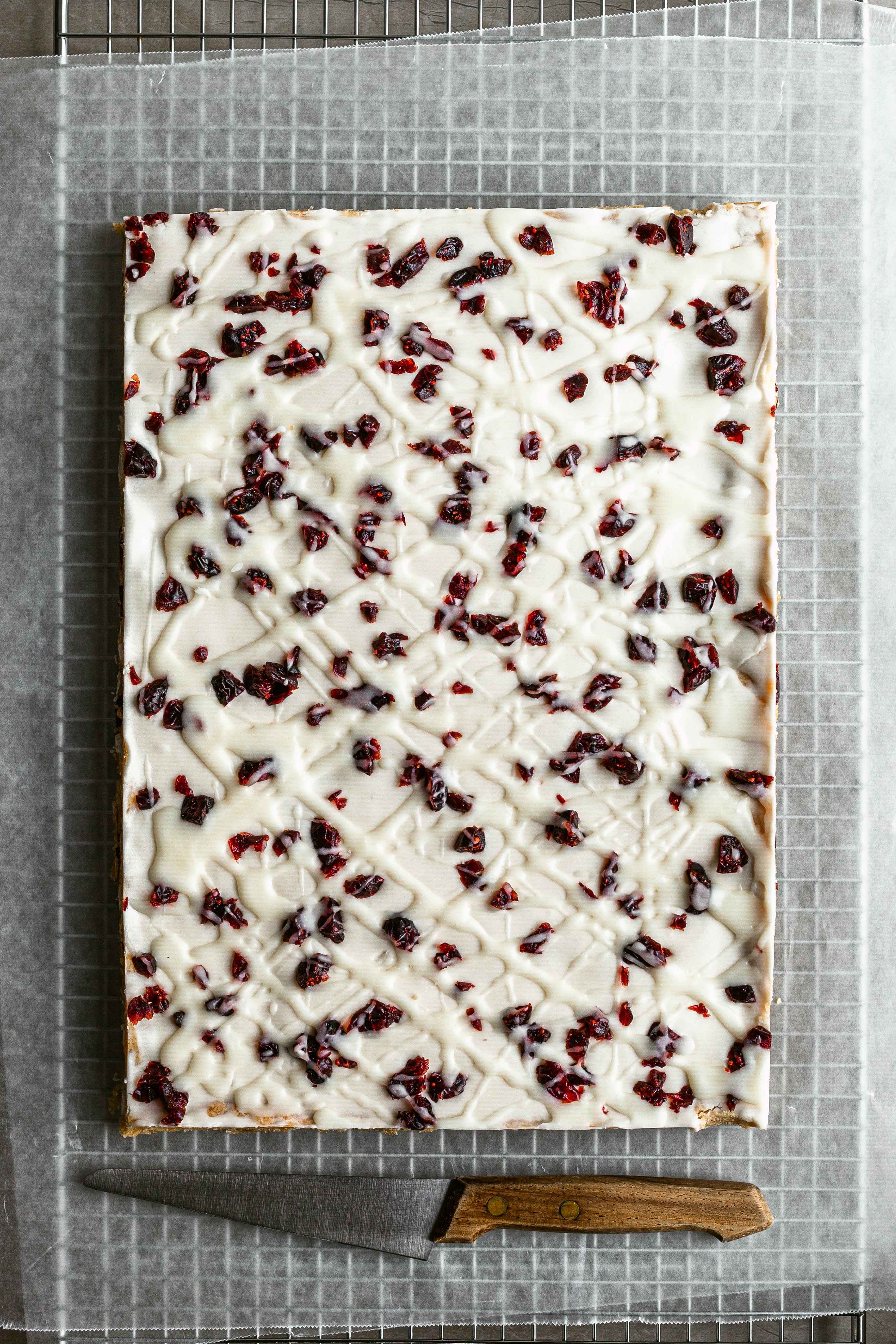 Vegan Bliss Bars flatlay, just before slicing on sheets of parchment paper beside a wood handled knife