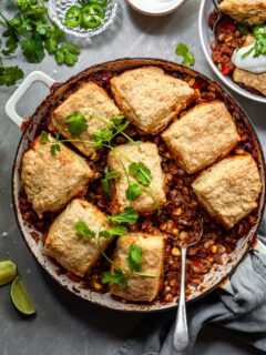 Chili pot pie in a white enamel skillet garnished with fresh cilantro leaves