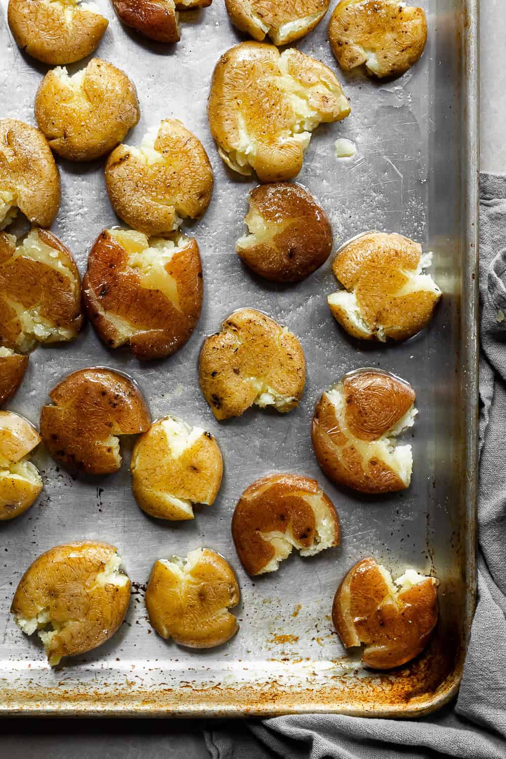 Smashed red and yellow baby potatoes on a baking tray