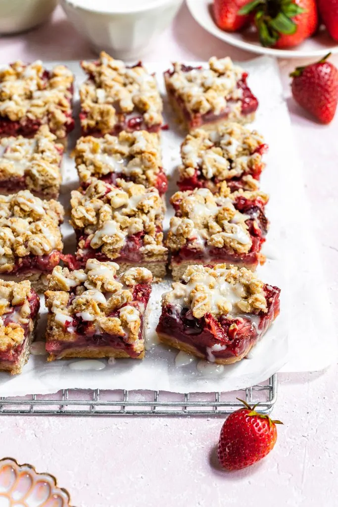 close up of strawberry crumb bars on a cooling rack, with white vanilla glaze just drizzled o tops