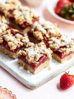 2 rows of strawberry oat bars on a narrow white cutting board