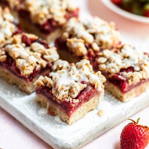 2 rows of strawberry oat bars on a narrow white cutting board