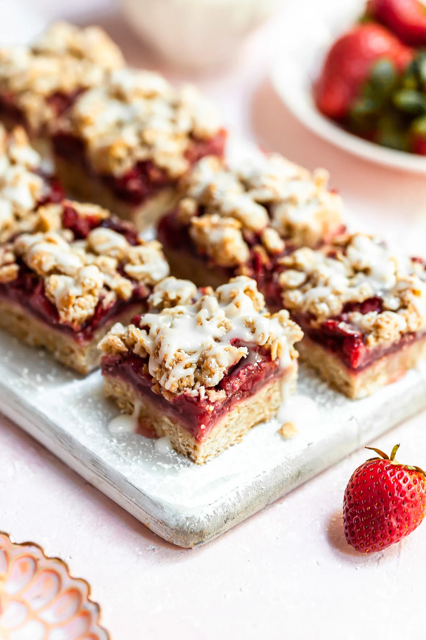2 rows of strawberry oat bars on a narrow white cutting board