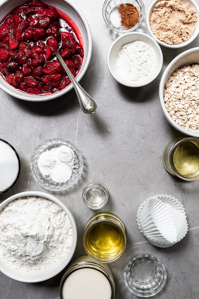 The ingredients for roasted strawberry muffins measured out in bowls on a marble counter