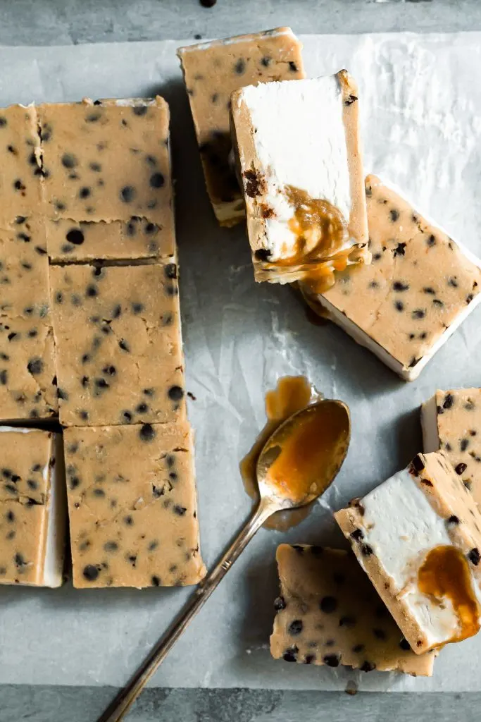 Cookie dough ice cream sandwiches  cut on parchment paper, some dripping with caramel
