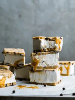 a stack of chocolate chip cookie dough ice cream sandwiches dripping with caramel