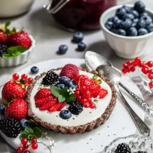 Breakfast table scene with a small tart willed with yogurt and topped with fresh berries