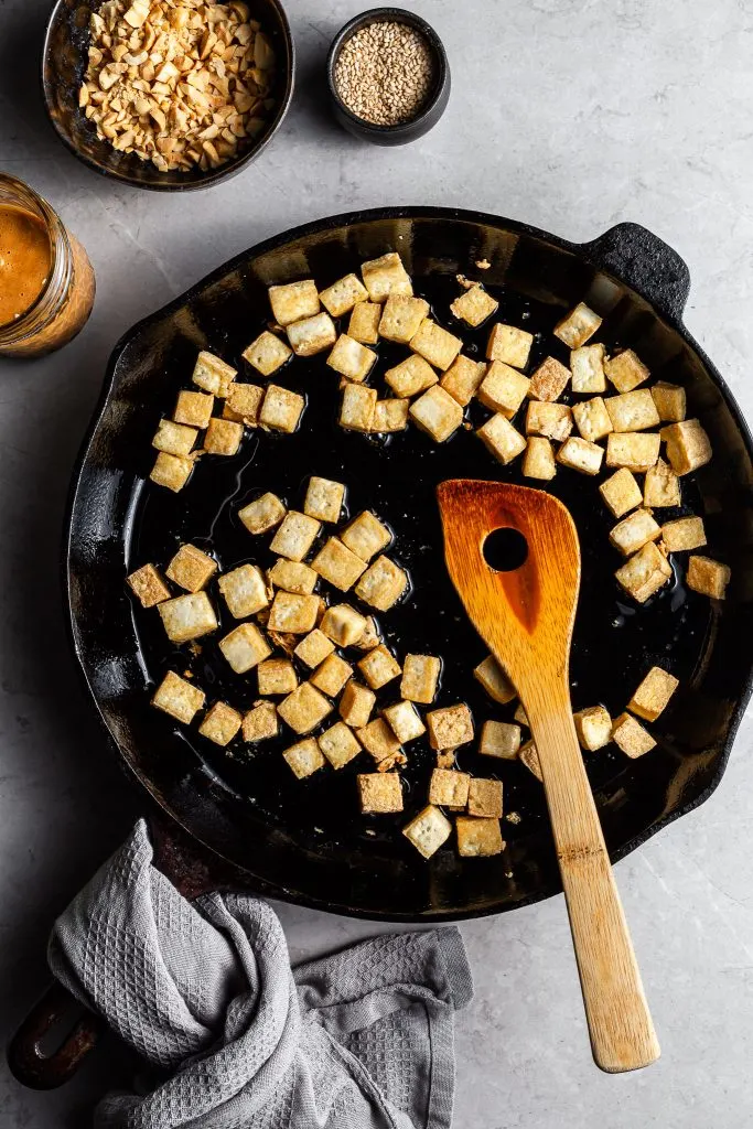 A cast iron skillet filled with crispy fried tofu cubes