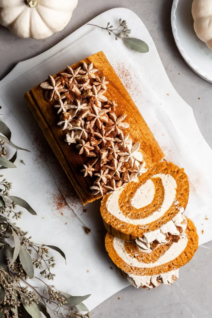 View looking down over a pumpkin dessert roll piped with ermine frosting and dusted with cinnamon
