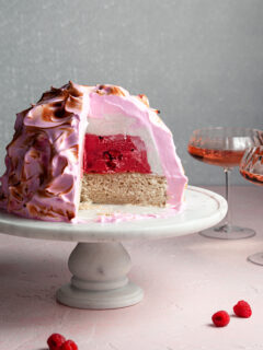 Pink meringue on a dome of ice cream cut with a slice missing. The center is white and dark pink
