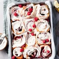 Aluminium baking pan filled with rapsberry sweet rolls covered in vanilla glaze