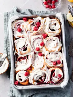 Aluminium baking pan filled with rapsberry sweet rolls covered in vanilla glaze