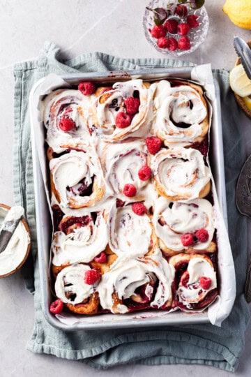 Aluminium baking pan filled with rapsberry sweet rolls covered in vanilla glaze
