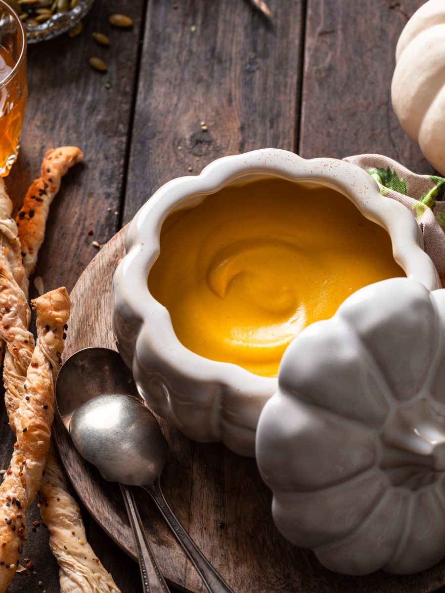 A white pumpkin shaped bowl filled with creamy roasted squash soup.