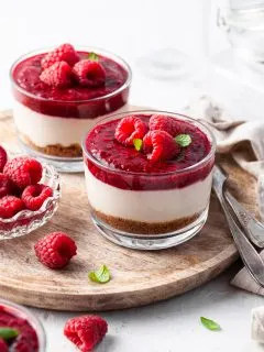 No Bake Vegan Cheesecake Jars garnished with raspberries, served on a wooden tray